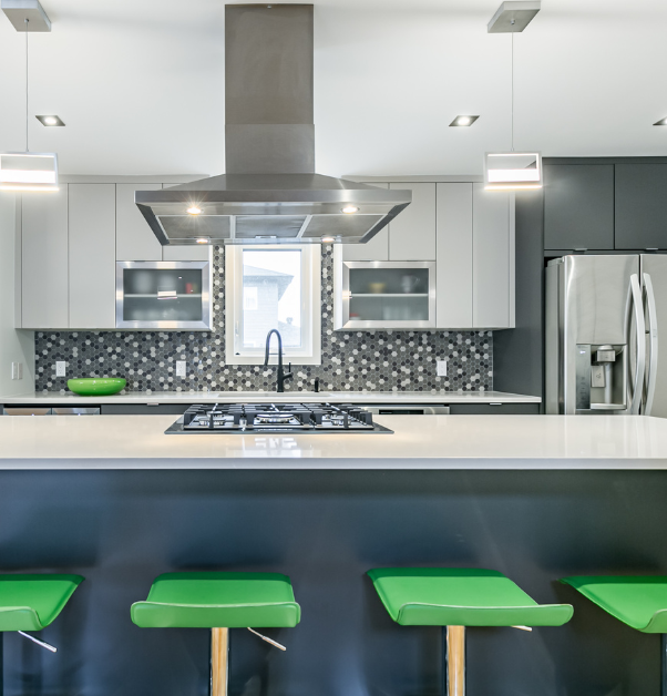 Transformed kitchen with grey quartz island, hexagonal tricolor mosaic backsplash, lime green stools and overhead hood