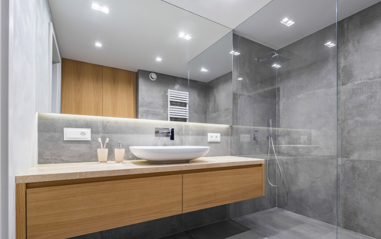 salle de bain moderne avec lumières encastrées au plafond et sous le miroir