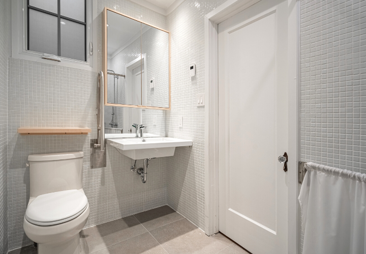 renovated accessible bathroom with adjustable mirror and grab bars
