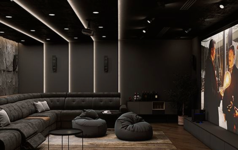 cinéma maison au sous-sol avec de grands canapés noirs et détails de plafond avec éclairage architectural