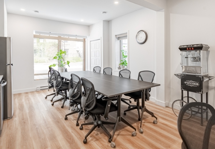 Large conference room and kitchenette completely renovated with classic style black furniture as well as white wall, backsplash, counter, and cabinets and matching black popcorn machine
