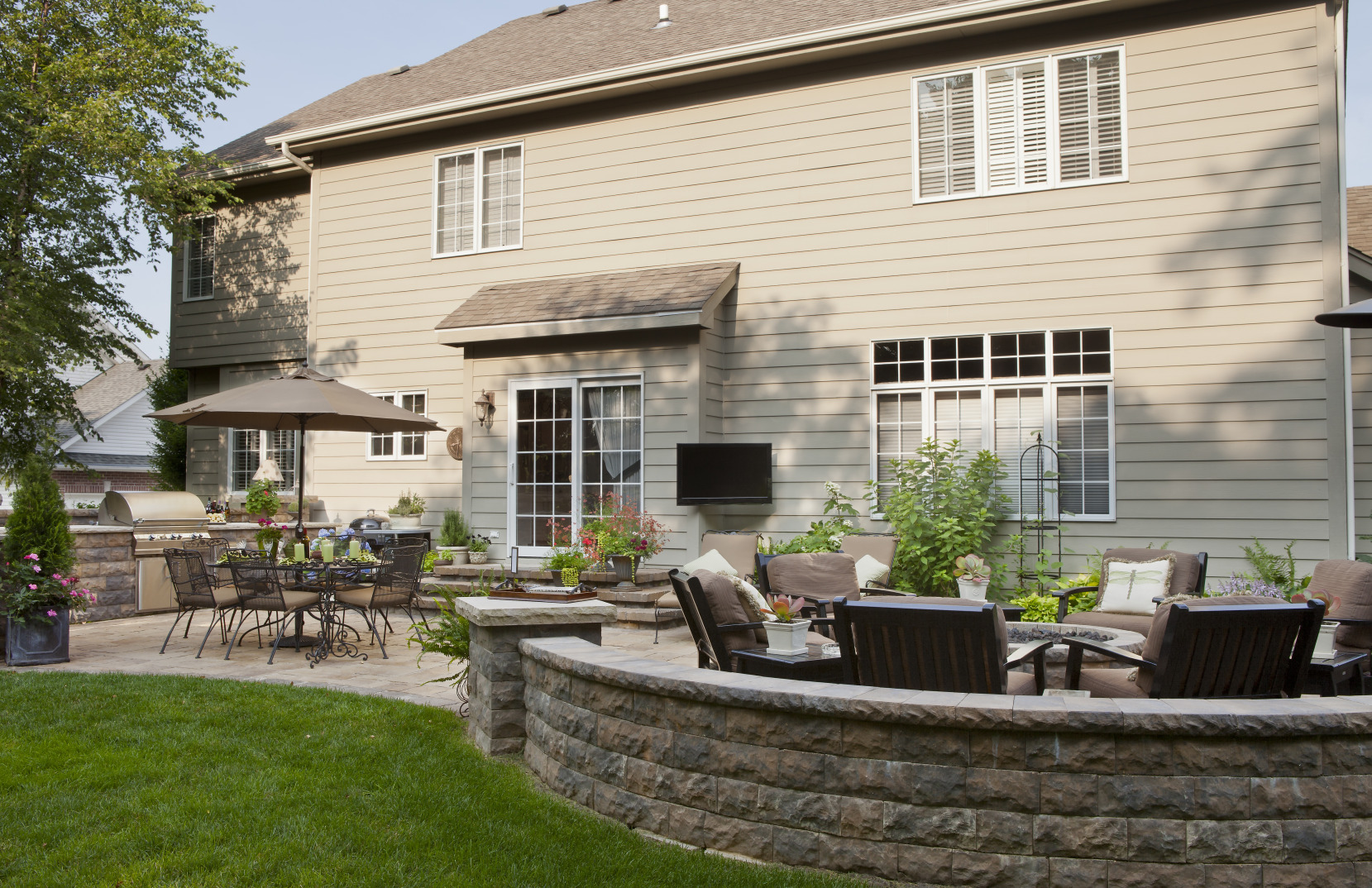  A new home construction with two seating areas on a stone patio.