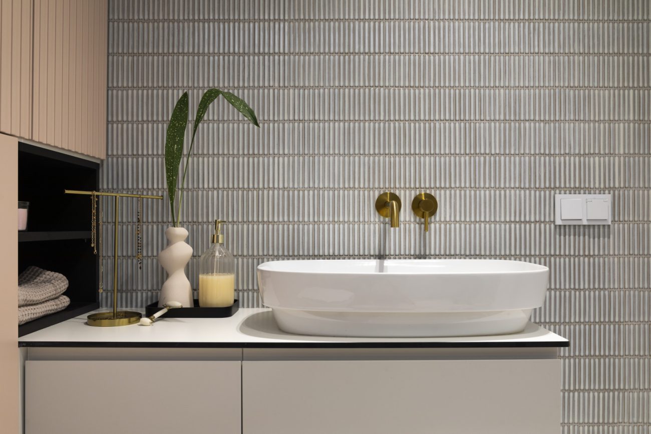 Bathroom with small blue kit kat ceramic tiles, white sink and gold faucet