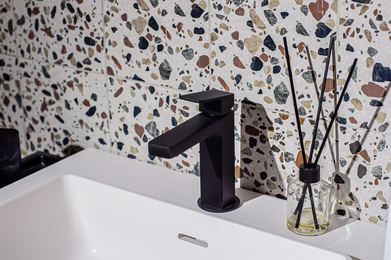 Bathroom with terrazzo quarry tiles, white sink and black faucet