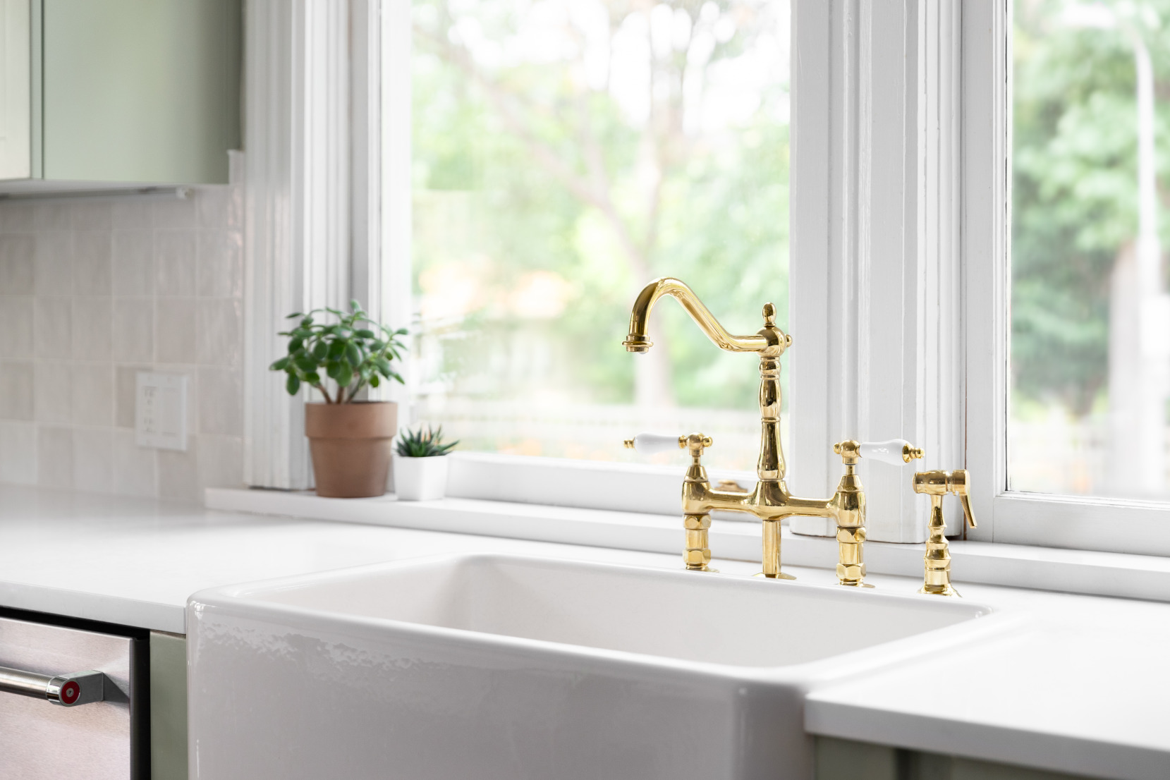 Gold faucet detail in a warm green kitchen