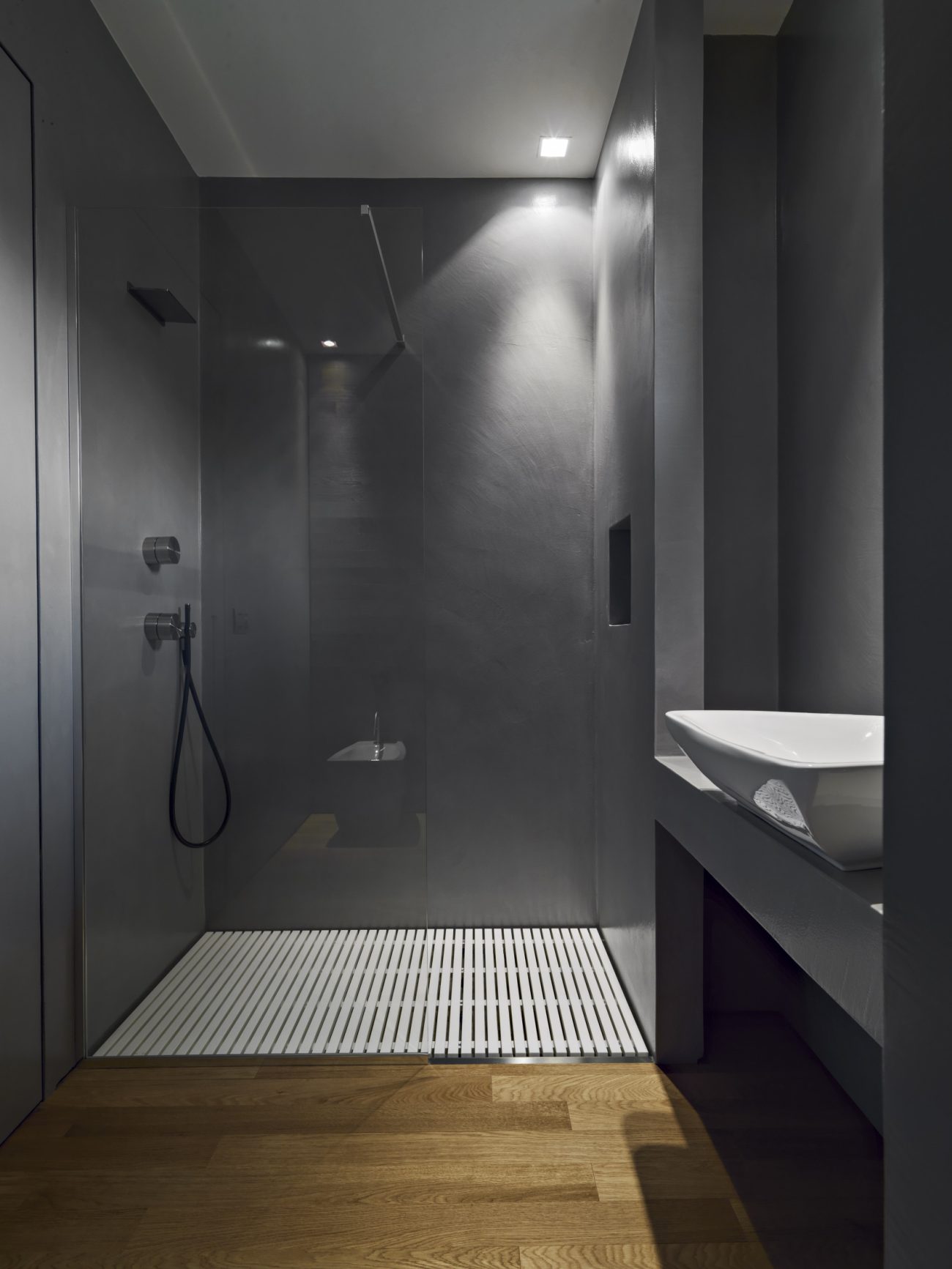 Interior of a contemporary bathroom with grey resin walls and subdued lights