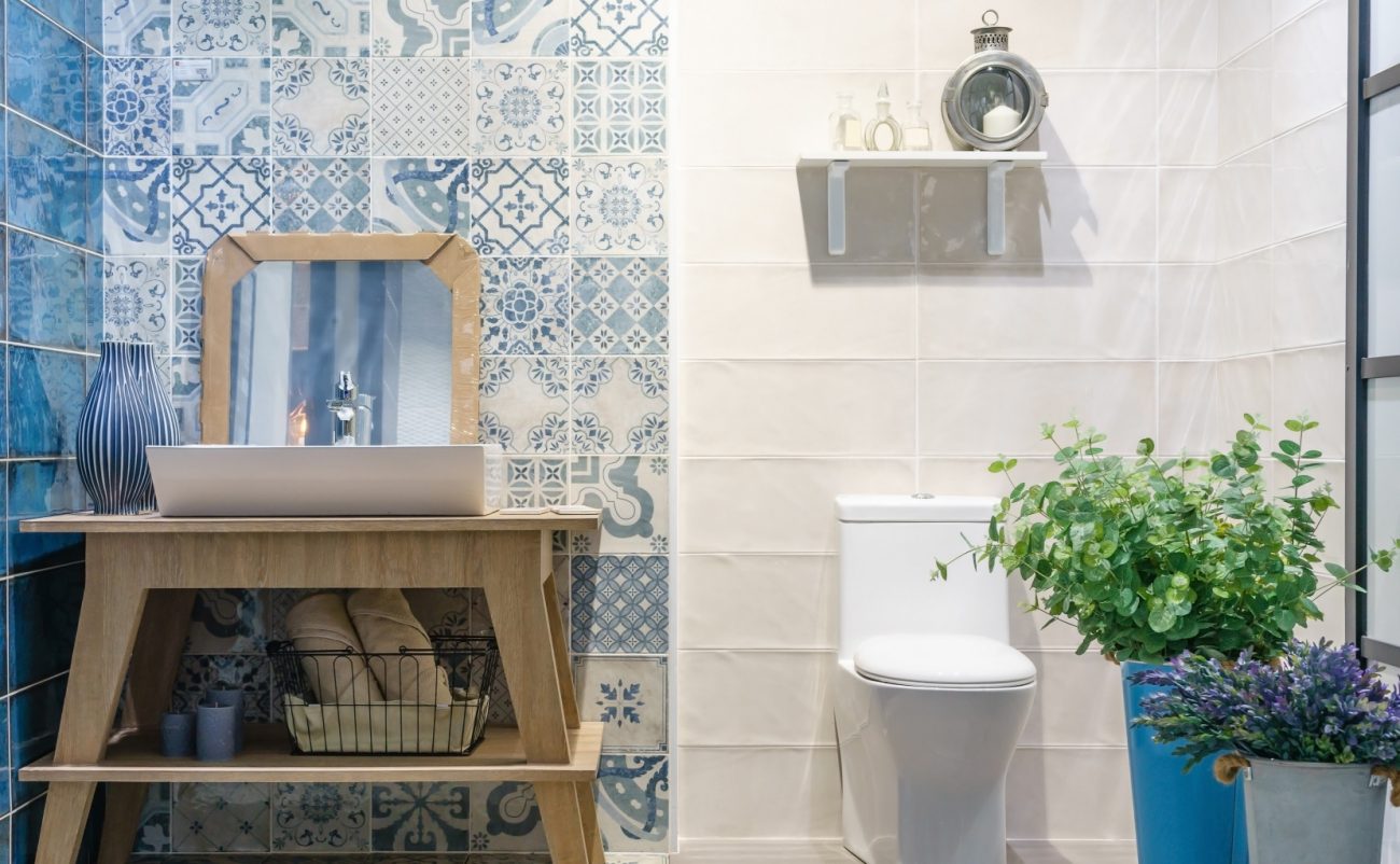 Modern bathroom interior with blue ceramic peel-and-stick, wooden vanity and toilet