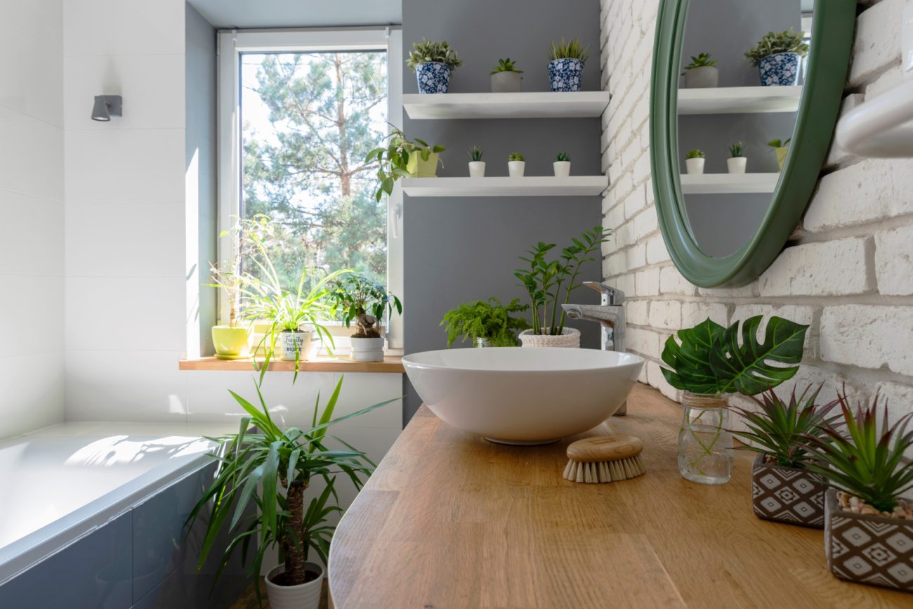 Salle de bain blanche avec comptoir en bois, mur de briques, lavabo en céramique et design moderne.