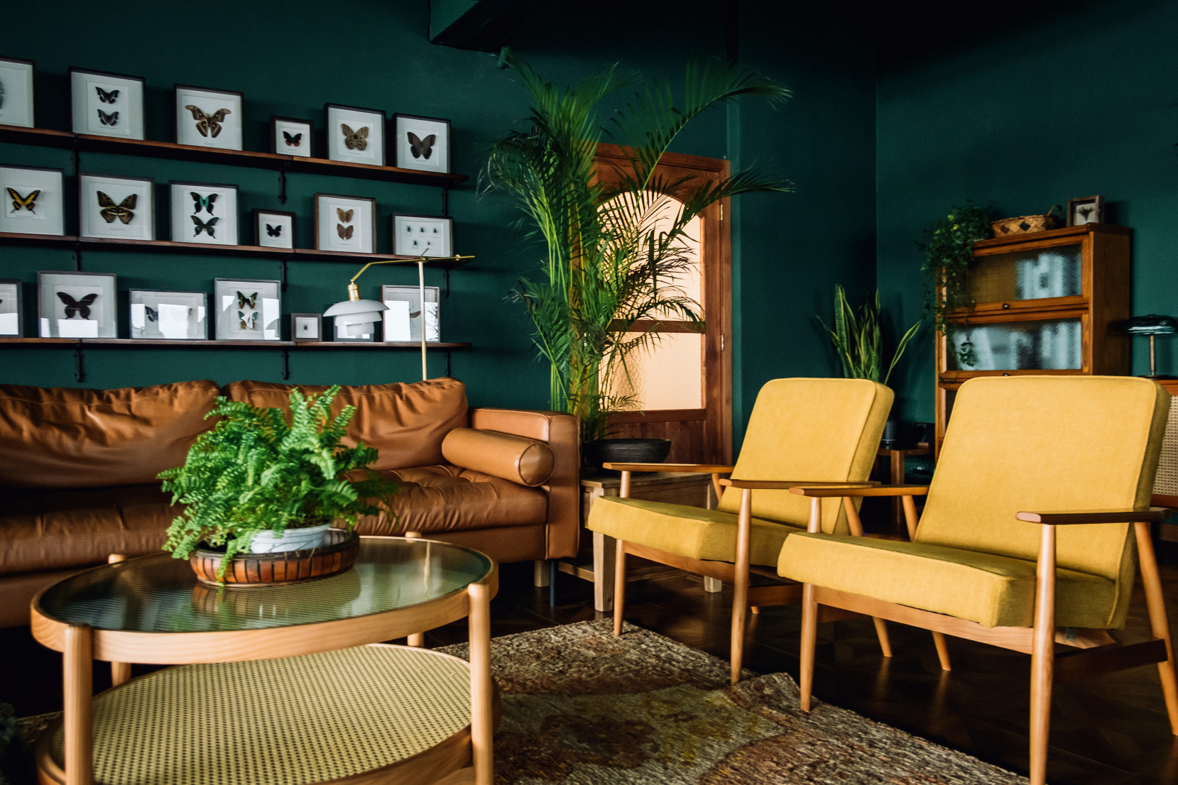 Salon avec des murs de couleur sarcelle, des accents en bois, des chaises jaunes et un canapé marron dans une nouvelle maison.