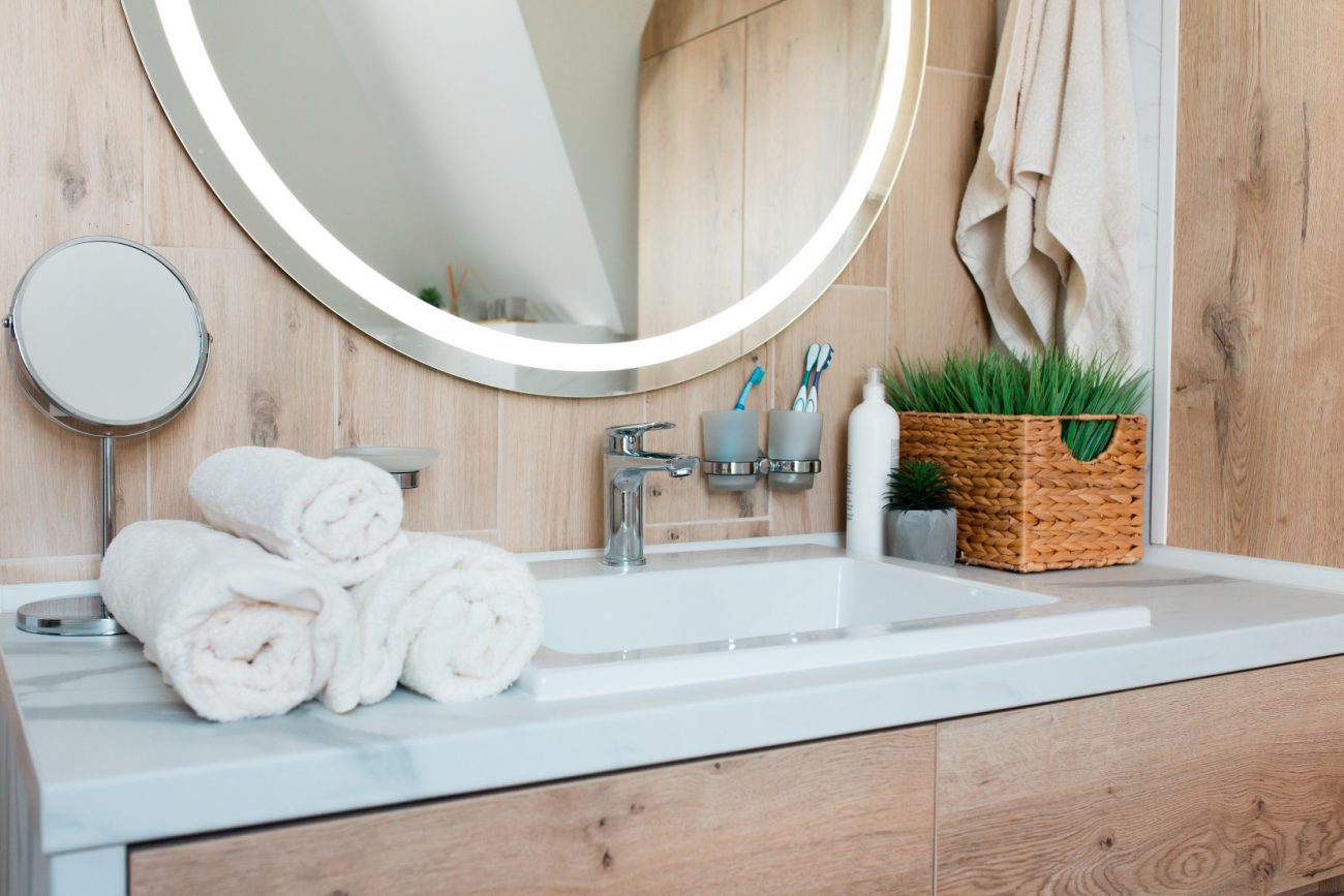 Wood-panelled bathroom with stone white countertop and led vanity mirror