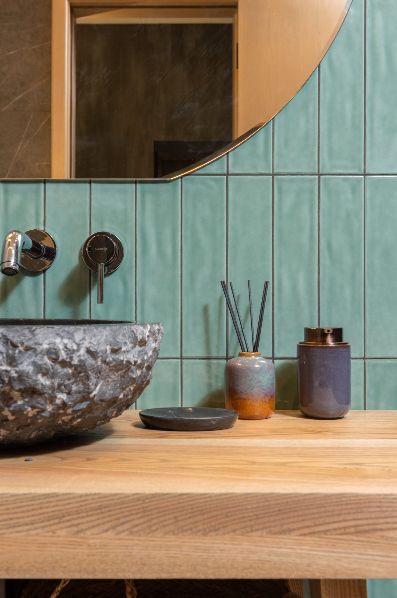 Bathroom with blue glass ceramic wall with wooden counter and stone vessel sink