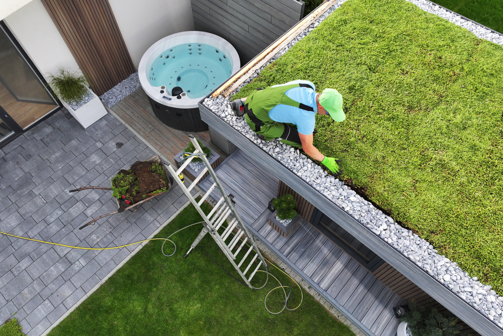 Paysagiste professionnel installant un toit vert sur un abri de jardin moderne