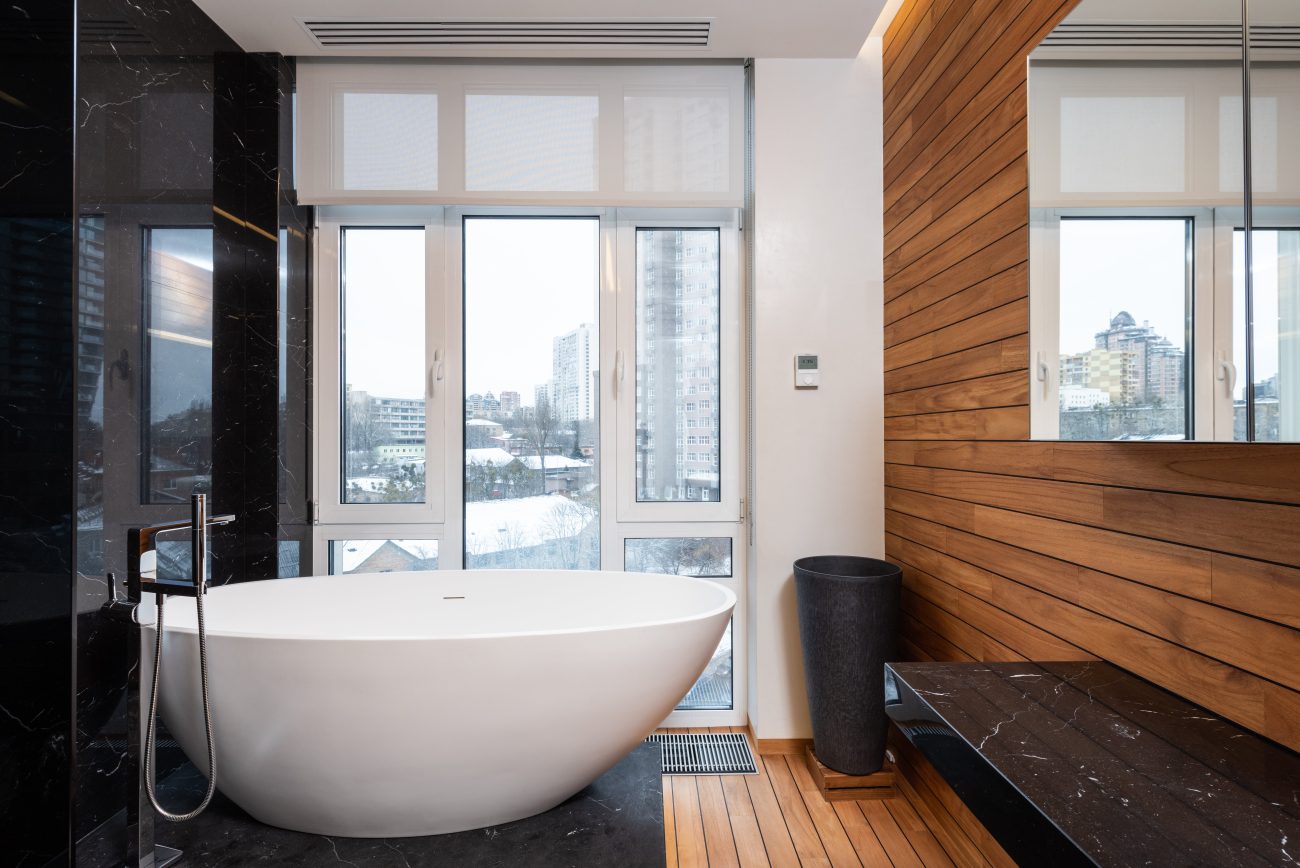 Freestanding bathtub on a podium in a bathroom with wooden slats