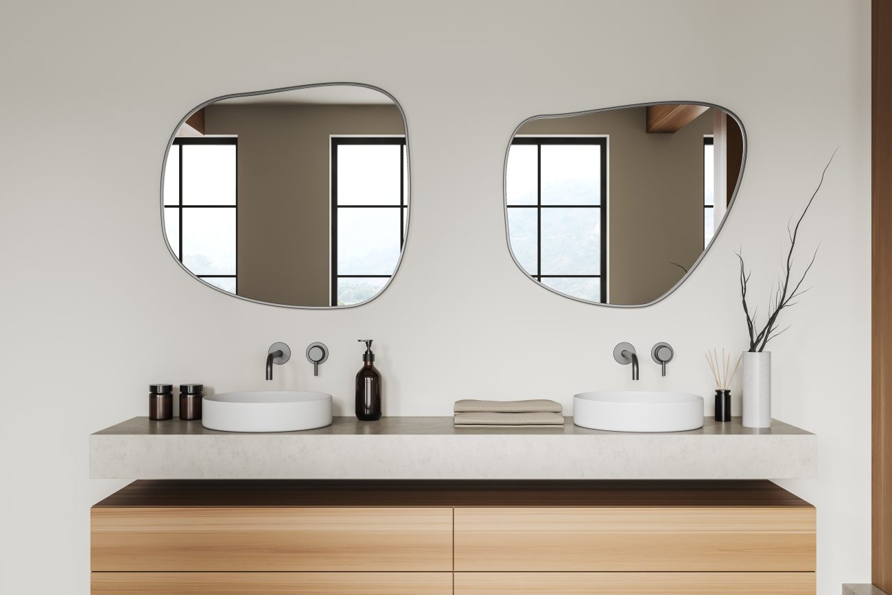 Bright bathroom with double sink, wooden chest of drawers and rounded mirrors
