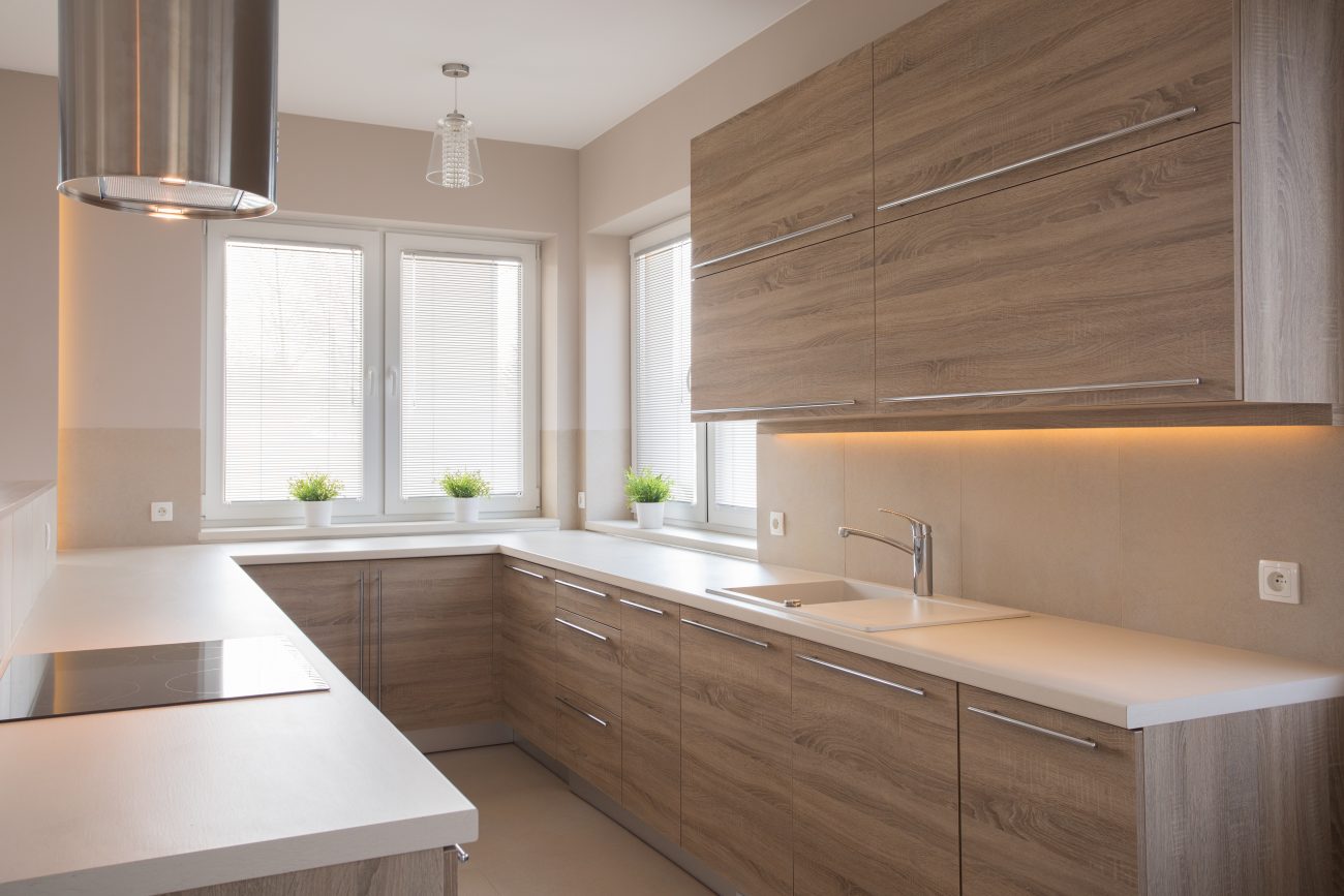 Bright U-shaped white kitchen with wooden cabinets and long stainless steel handles