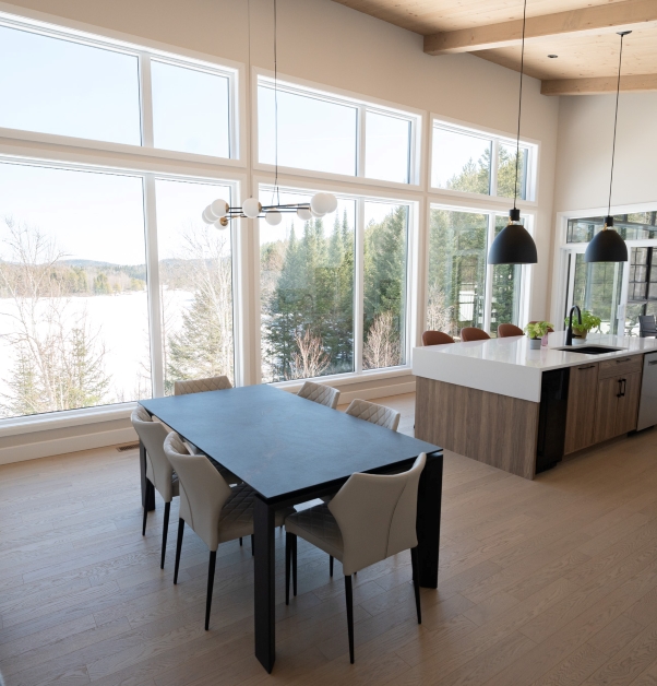 Modern and white open concept kitchen and dining room, large windows, cathedral wood ceiling with lake view.